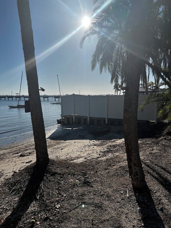 A beach with palm trees, a pier, and a building with a flat roof.