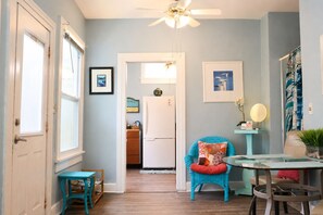 A compact kitchen with a refrigerator, a dining area with a table and chairs, and a ceiling fan. - Waterfront 1BR Retreat w/Shared Private Beach + Walk to Beach Blvd (Gulfport)