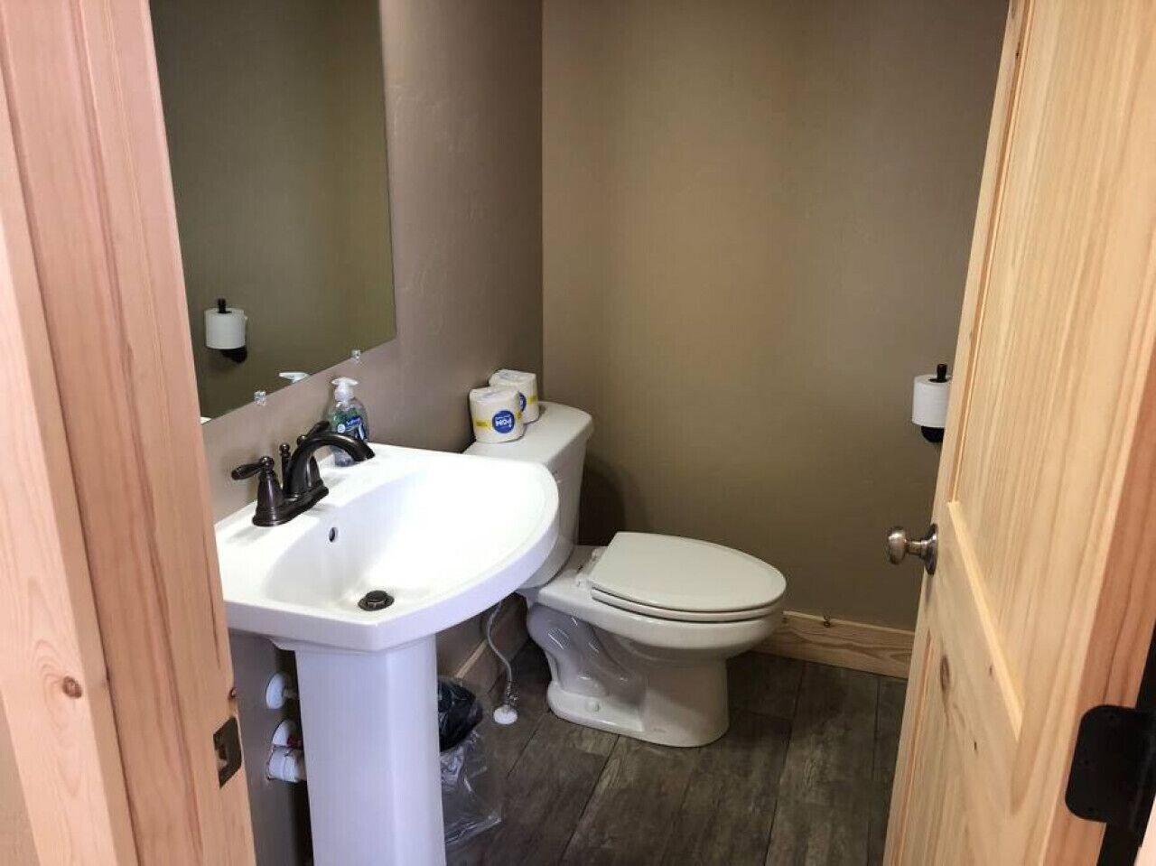 A small bathroom with a white sink, toilet, and mirror.