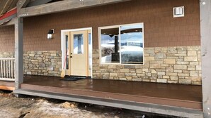Un bâtiment à l’extérieur en pierre et en brique, avec un porche en bois et une porte.