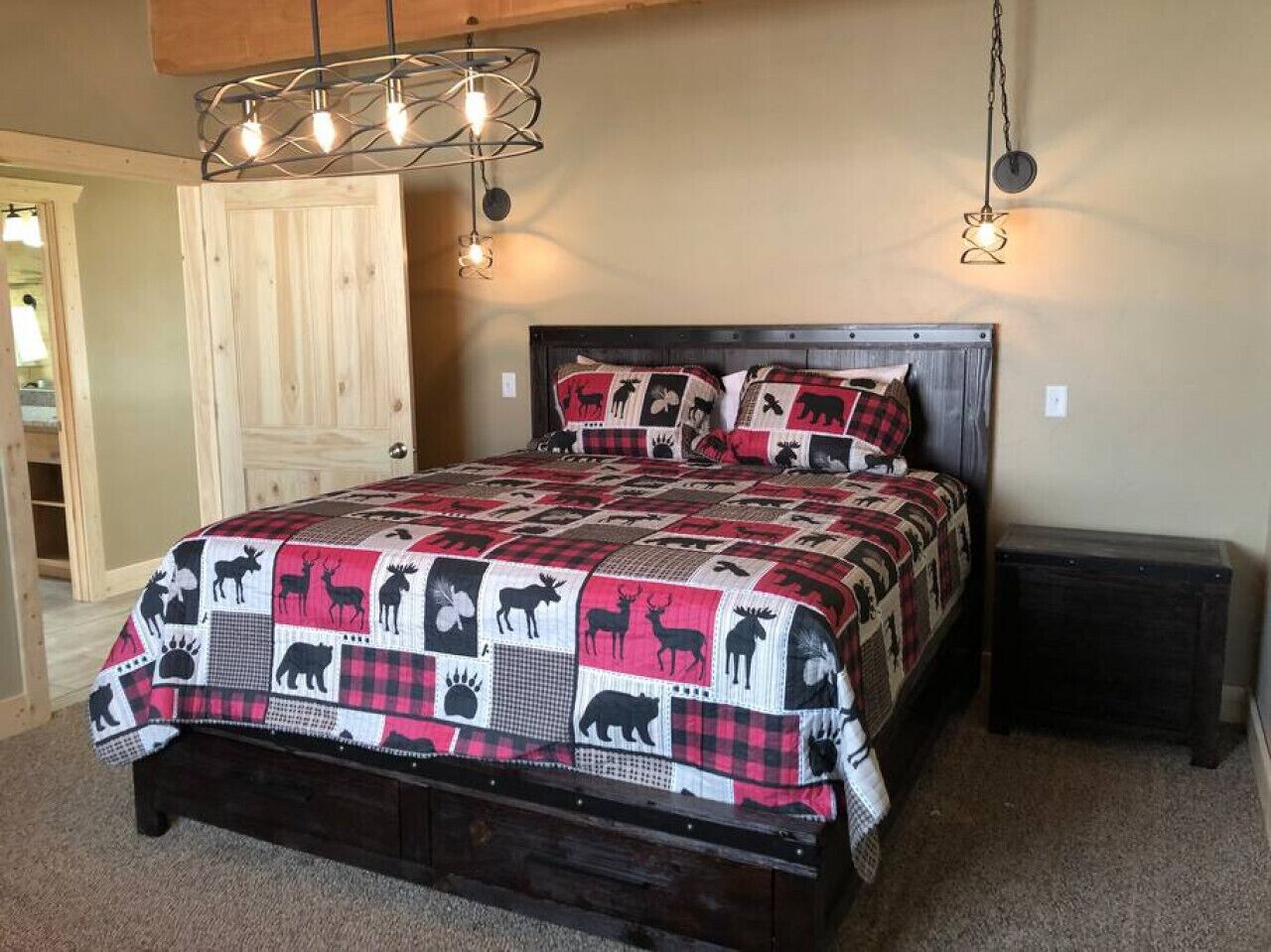 A bedroom with a bed, wooden headboard, and a quilt with animal prints.