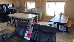 Une cuisine moderne avec des meubles en bois, un îlot central et un coin repas agrémenté d’une banquette.