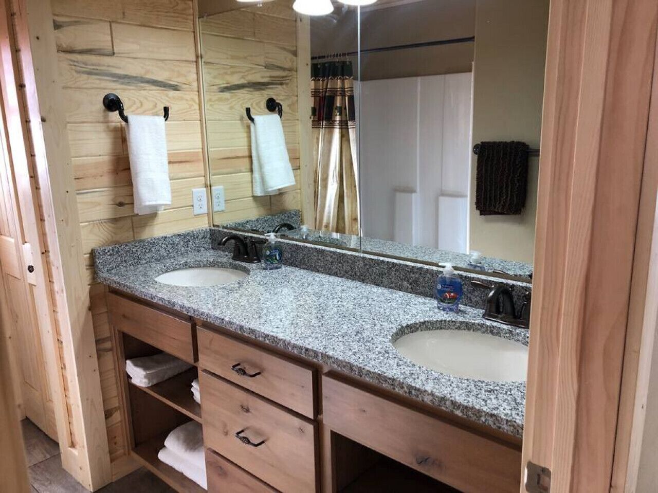 Een badkamer met twee wastafels, houten kastjes en een grote spiegel.