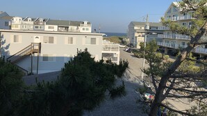A coastal hotel with multiple balconies, a staircase leading to the upper floors, and a view of the sea.