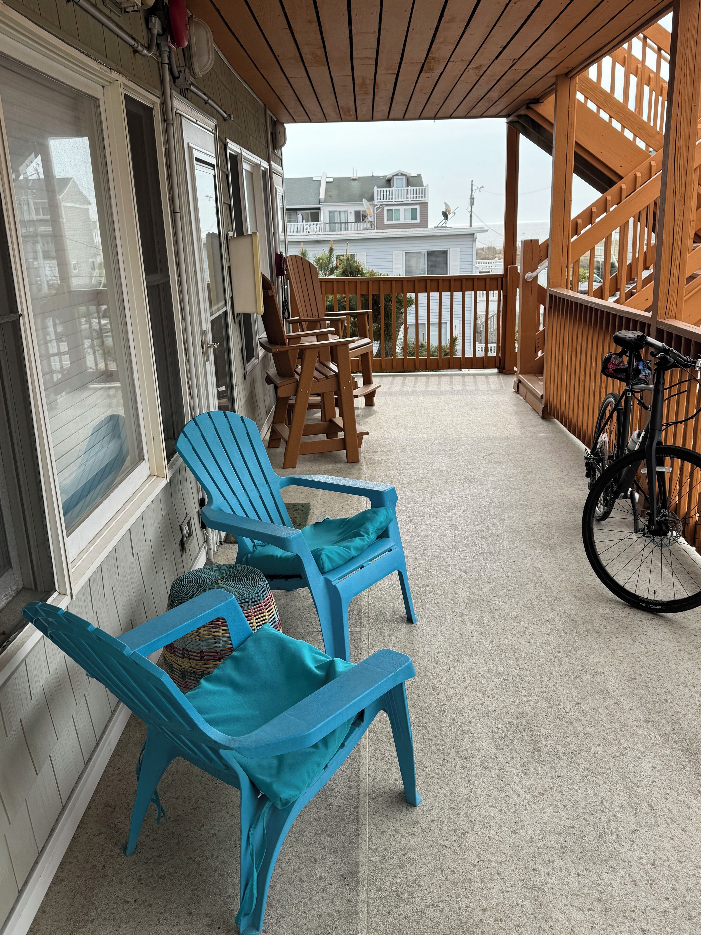 Un espace extérieur abrité, avec des chaises en bois et un vélo.