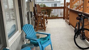 A covered outdoor area with wooden chairs and a bicycle.