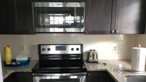 A modern kitchen with stainless steel appliances, dark cabinetry, and a granite countertop.