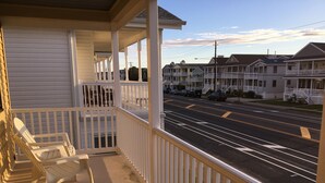 A porch with white railings and a view of a street with houses.