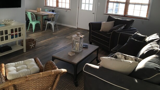 A living room with a TV, two windows, a dining area, and a sofa.