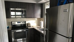 A modern kitchen with stainless steel appliances, dark cabinetry, and a granite countertop.