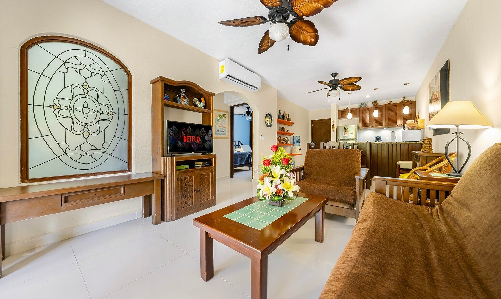 A living room with a wooden coffee table, a sofa, a TV, and a decorative wall piece.