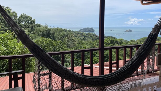 A hammock on a balcony overlooking a coastal landscape with dense greenery and distant islands. - Gorgeous Views of Pacific and Rainforest (manuel antonio)