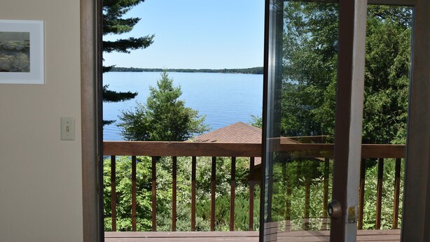 A balcony with a view of a lake and trees. - Waterfront Lake House on Scenic Lake Nokomis (Tomahawk)