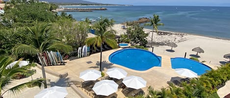 Et resort med to swimmingpools, strandstole og palmer.