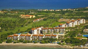 Un resort con varias edificaciones, un campo de golf y una playa.