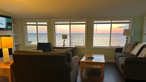 Una sala de estar con vista al océano, un televisor y dos sofás.