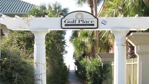 Un chemin menant à une zone délimitée par une barrière, sur laquelle est apposée une pancarte indiquant « Gulf Place ».