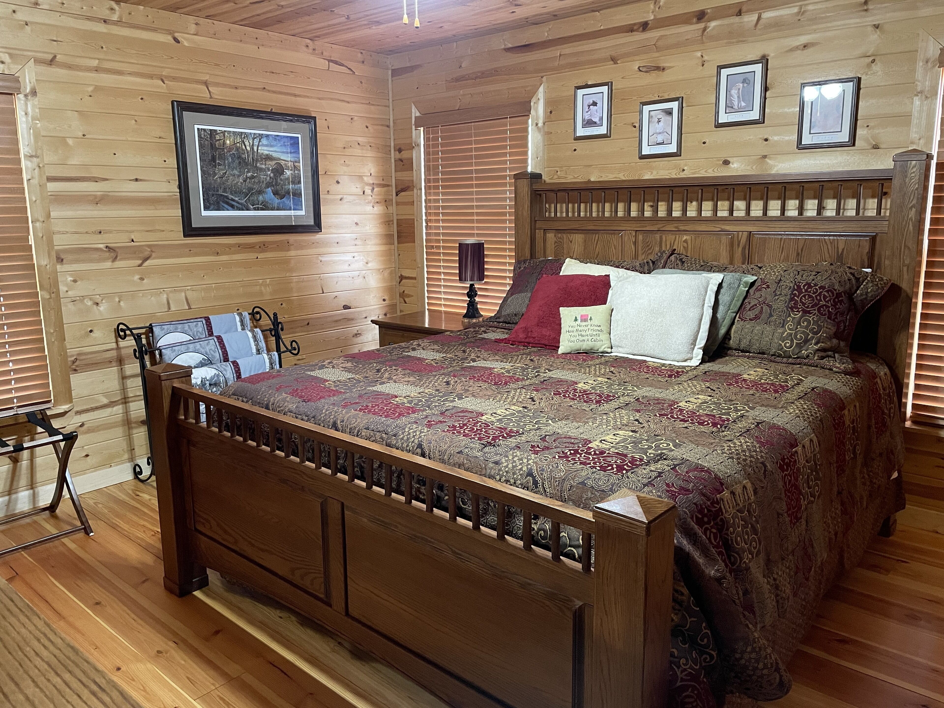 A wooden cabin-style bedroom with a bed, a nightstand, and a framed picture on the wall.