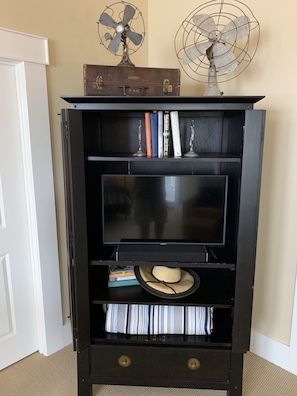 Entertainment center features a flat-screen TV and storage for books and personal items.
