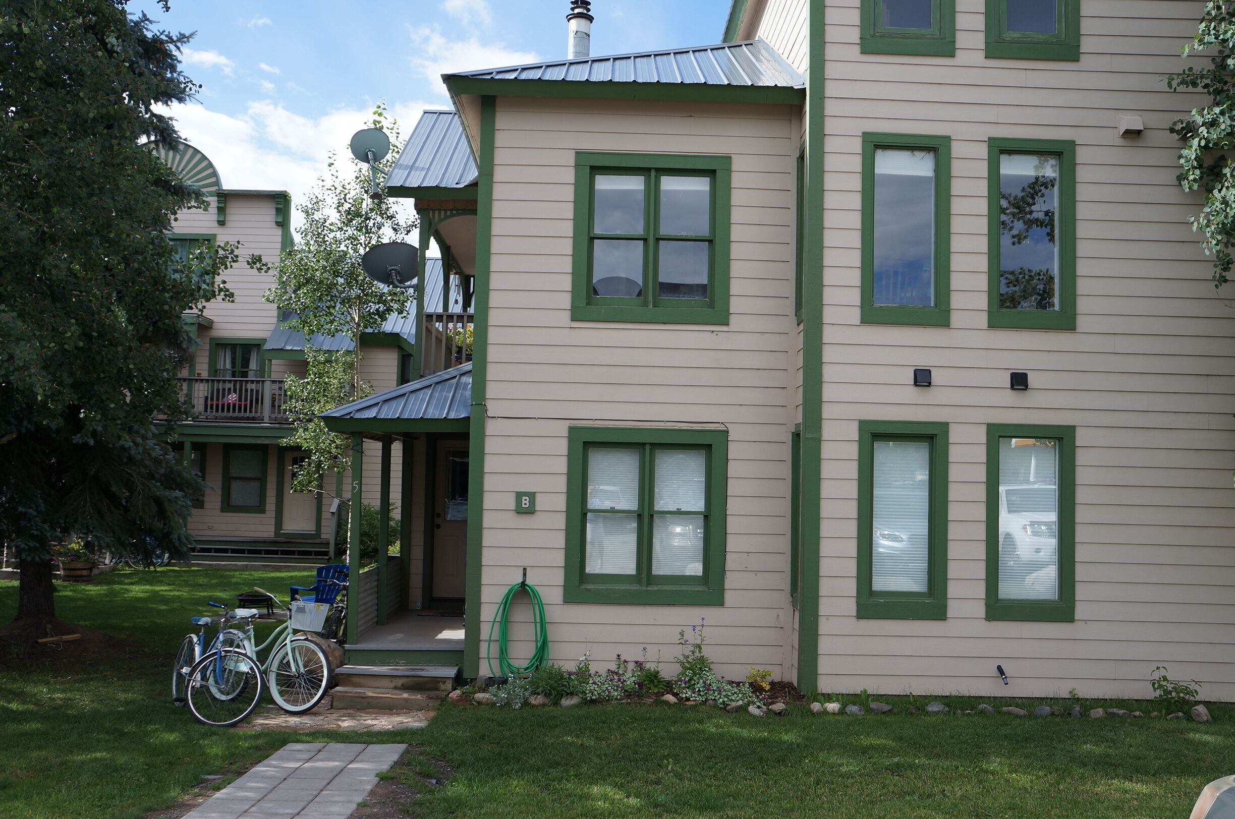 A two-story house with green-framed windows and a porch.