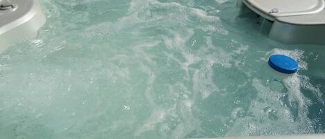 A hot tub with clear water, a blue lid, and a built-in seat.