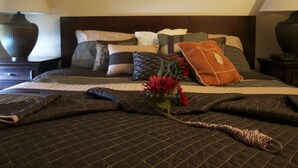 A neatly made bed with a quilted brown cover, multiple pillows, and a decorative pillow with a leaf design. A bouquet of red flowers is placed on the bed. - ** Ypcfitness & Accomodations ** (Invermere)