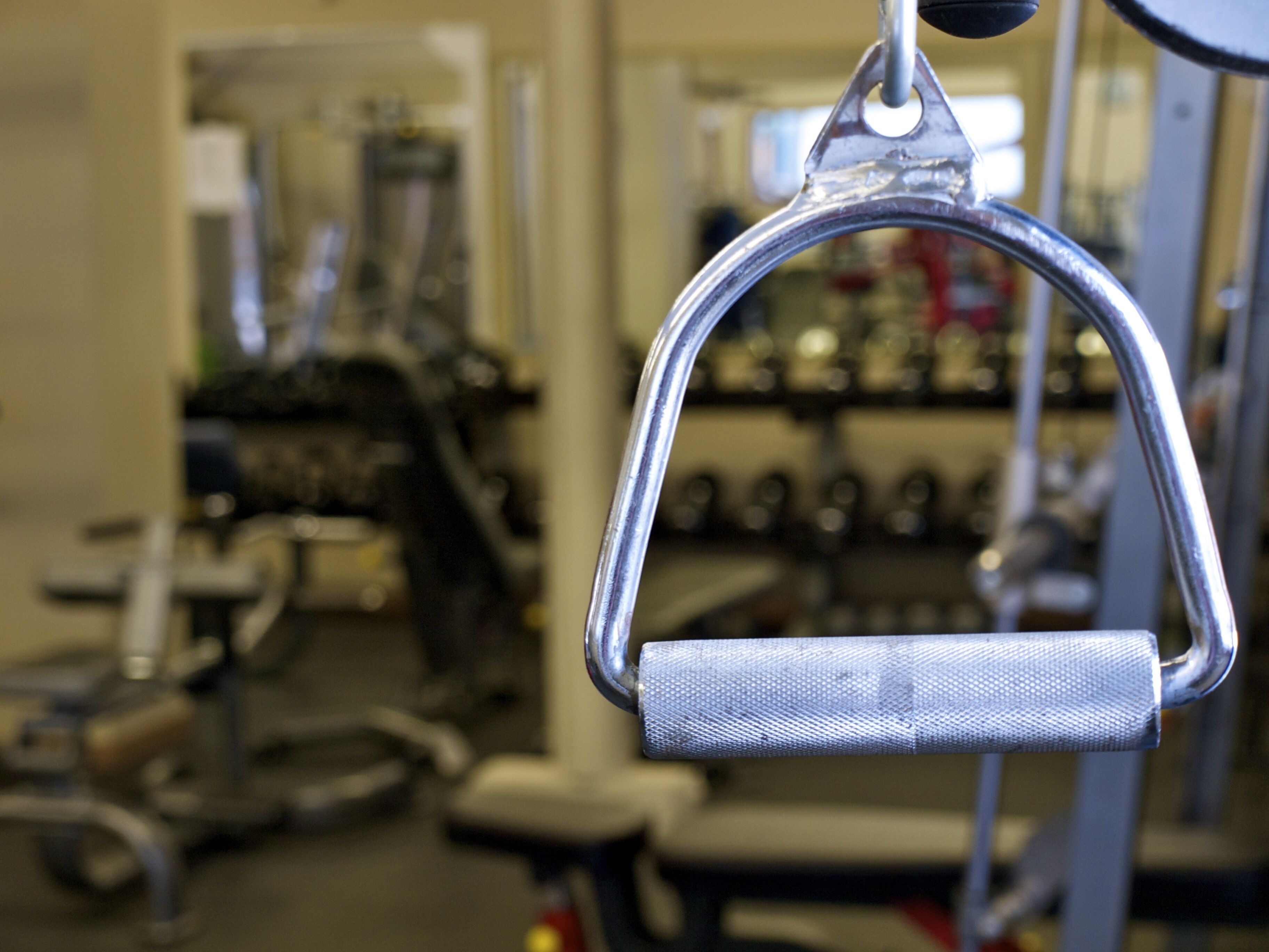 Primer plano de una barra de ejercicios metálica con empuñadura texturizada, como parte del equipamiento de un gimnasio.
