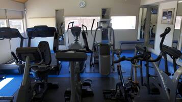 Een fitnessruimte met diverse trainingsapparaten, waaronder loopbanden, crosstrainers en krachtapparaten.