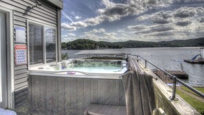 Ein Whirlpool auf einer Terrasse mit Blick auf einen See und Hügel.