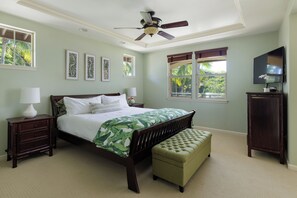 Une chambre à coucher comprenant un lit, des tables de chevet, un téléviseur et un ventilateur de plafond.