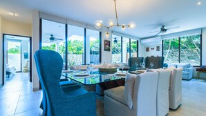 Ein moderner Essbereich mit einem Glastisch, blauen Stühlen und weißen Sofas.
