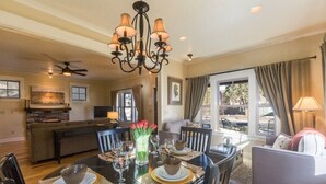 A dining area with a chandelier, a table set for four, and a kitchen in the background. - Bluebird Day - Harmon Park Bungalow, Charming 2BR perfect for getaways! (Bend)