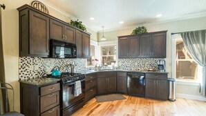 A modern kitchen with dark wood cabinets, a black microwave, a stove, and a dishwasher. - Bluebird Day - Harmon Park Bungalow, Charming 2BR perfect for getaways! (Bend)
