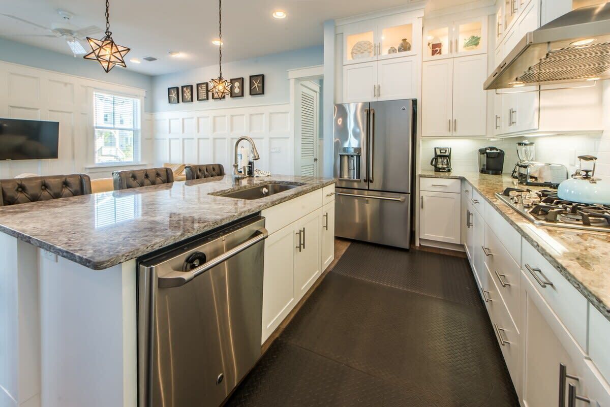 A modern kitchen with stainless steel appliances, a marble countertop, and a built-in dishwasher.
