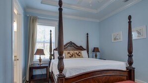 Un letto a baldacchino con testiera in legno, due comodini e una panca imbottita rossa.
