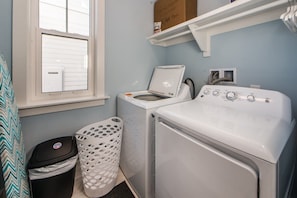 A laundry area with a washing machine, dryer, and a window with blinds.