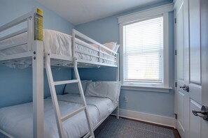 A bunk bed room with a window and a door.