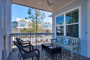 A covered porch with wicker chairs and a bench, a ceiling fan, and a view of neighboring houses. - 6-Seater Golf Cart & 6 Bikes! Spacious Porches! Balconies w/ Views of the Pond! Latitude Adjustment (Santa Rosa Beach)