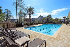 A swimming pool with lounge chairs and a tiled deck.