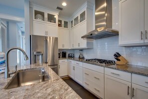 A modern kitchen with white cabinetry, stainless steel appliances, and a granite countertop.