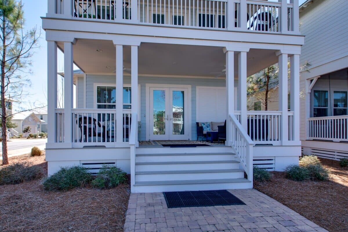 A two-story house with a covered porch, a front door, and a staircase leading to the entrance.