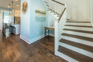 A spacious kitchen with modern appliances, a dining area with a bar seating, and a staircase leading to an upper level.