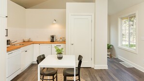 A modern kitchen with white cabinets, a wooden countertop, and a dining area with a white table and black chairs. - Lovely Studio/Guesthouse in Lake Oswego (Lake Oswego)