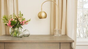 A wooden desk with a vase of flowers, a glass, and a gold lamp. - Lovely Studio/Guesthouse in Lake Oswego (Lake Oswego)