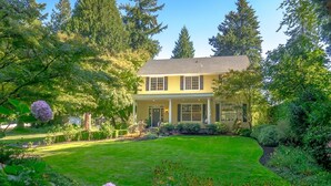 A two-story house with a front porch, surrounded by a well-maintained garden with various plants and flowers. - Lovely Studio/Guesthouse in Lake Oswego (Lake Oswego)