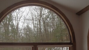 Ein Zimmer mit einem großen Bogenfenster mit Blick auf eine verschneite Landschaft mit Bäumen und einem gefallenen Baum.