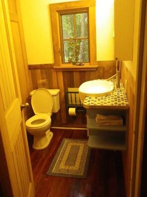 Ein kleines Badezimmer mit Toilette, Waschbecken und Fenster.