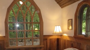 Ein Schlafzimmer mit einem großen Bett, Holzwänden und einem Fenster mit Blick auf Bäume.