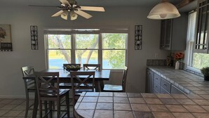 A kitchen with a dining table, chairs, a ceiling fan, and a window with a view of trees. - Lake Travis Waterfront Home - 4 Bed, 2 Bath, spectacular views, & private dock (Austin)