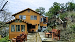 A two-story wooden house with a deck, outdoor seating, and a staircase leading to a second level. - Lake Travis Waterfront Home - 4 Bed, 2 Bath, spectacular views, & private dock (Austin)